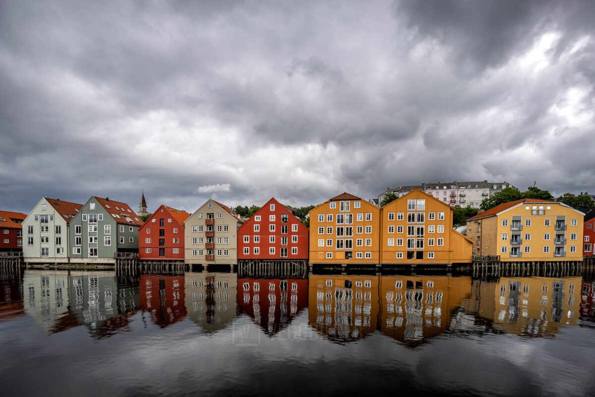 Fargerike trehus langs Nidelva i Trondheim med dramatisk himmel og vakre refleksjoner i vannet., fotokunst veggbilde / plakat av Eirik Sørstrømmen