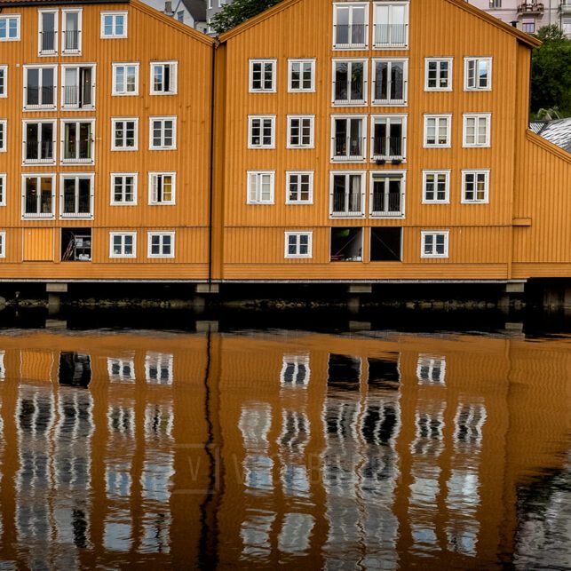 Fargerike trehus langs Nidelva i Trondheim med dramatisk himmel og vakre refleksjoner i vannet., fotokunst veggbilde / plakat av Eirik Sørstrømmen